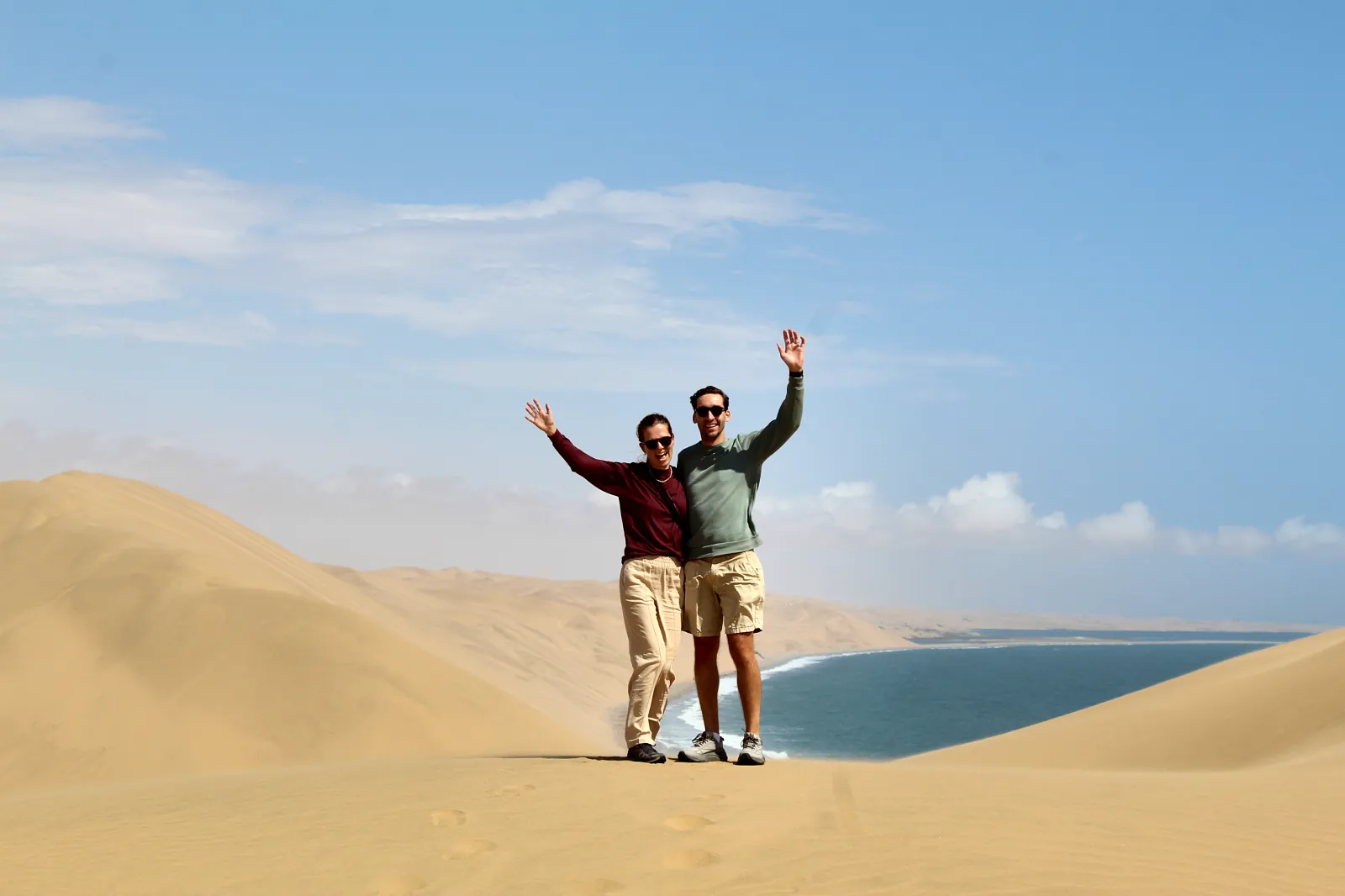 Guests waving from a dune above the Sandwich Harbour lagoon